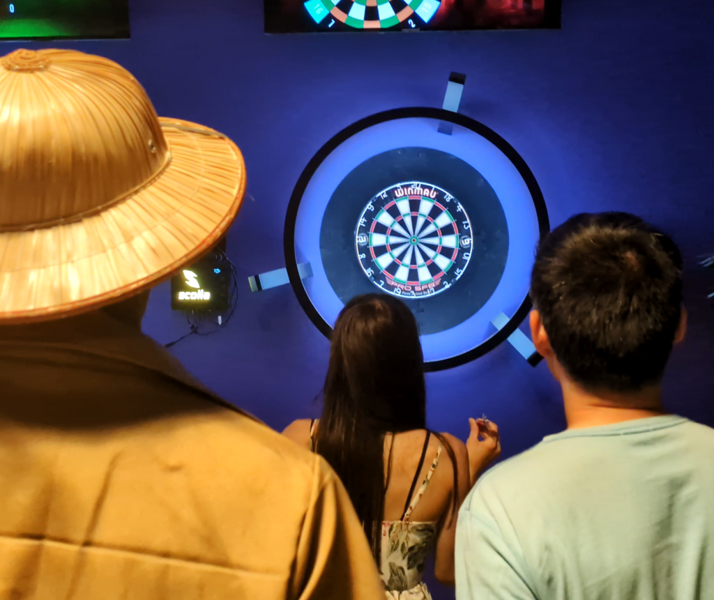 Groupe d'amis qui jouent aux fléchettes connectés chez Konvivio Béziers.